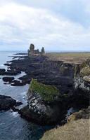 svart lavasten havsklippor på kusten av island foto