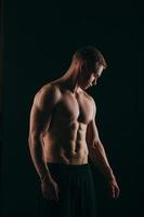 muskulös ung man visar hans biceps isolerad på svart bakgrund