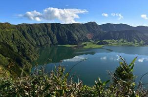 grön frodig kulle som omger den blå sjön på Azorerna foto