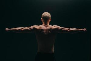 muskulös ung man visar hans biceps isolerad på svart bakgrund