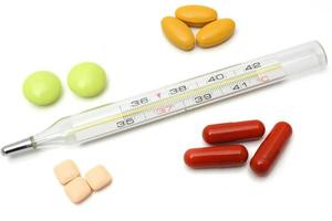 sjukdomskoncept med termometer och tabletter