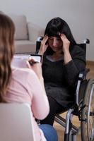kvinna på rullstol pratar med terapeut foto