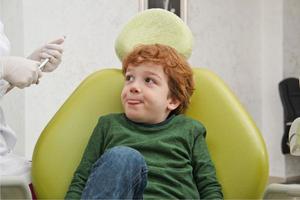 liten söt pojke som sitter i stol hos tandläkaren