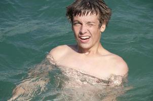glad tonåring pojke som simmar i vattnet i lake bled foto