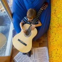 liten pojke spelar gitarr och sjunger på balkongen foto