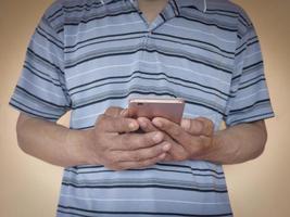 en asiatisk man som bär en blårandig skjorta som står och håller i en telefon foto