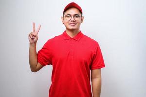 asiatisk kurirman iförd leveransuniform och keps visar och pekar upp med fingrar nummer tio medan han ler självsäkert foto