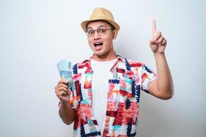 ung asiatisk man som håller pengar överraskad med en idé eller fråga som pekar finger foto