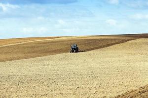 traktor som plöjer åkrarna foto