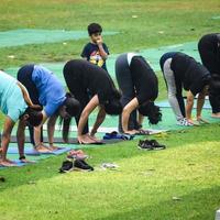 New Delhi, Indien, 18 juni 2022 - gruppyoga träningsklass surya namaskar för människor i olika åldrar i lodhi garden, internationella yogadagen, stor grupp vuxna som deltar i en yogaklass i parken foto