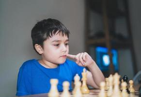 koncentrerad ung pojke utvecklar schackstrategi, spelar brädspel med förälder hemma. aktivitet eller hobby för familjekoncept foto