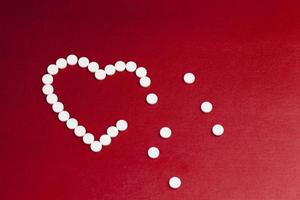 medicinska läkemedel tabletter staplade på en röd bakgrund i form av ett hjärta foto