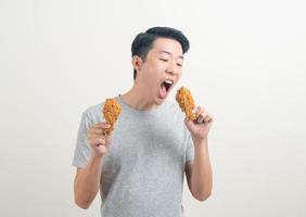 ung asiatisk man med stekt kyckling till hands foto