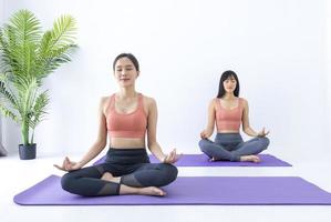 asiatisk kvinna som utövar yoga inomhus med enkel och enkel position för att kontrollera andning in och ut i meditationsställning foto