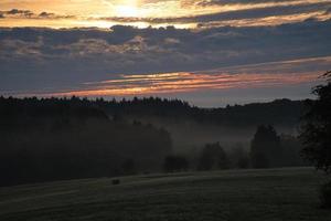 stigande sol på dimmig äng på morgonen i saarland foto