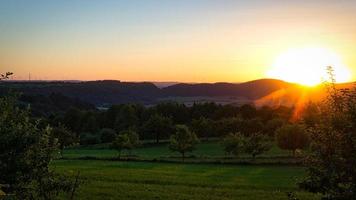 solnedgång i saarland på en äng med träd och utsikt in i dalen. foto