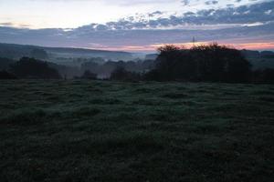 stigande sol på dimmig äng på morgonen i saarland foto