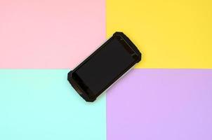 svart stötsäker smartphone ligger på en pastellfärgad bakgrund foto