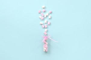 marshmallow sprayas från en liten glasbehållare på en blå bakgrund. foto