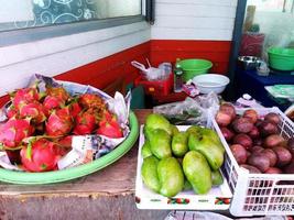 många frukter med drakfrukt och mango till försäljning på den lokala gatumatmarknaden. färskhet frukt på korgen foto
