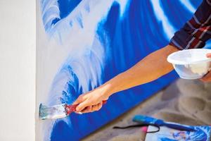 kvinnlig konstnär som arbetar på abstrakt akrylmålning, hand som håller pensel, stor duk utomhus foto