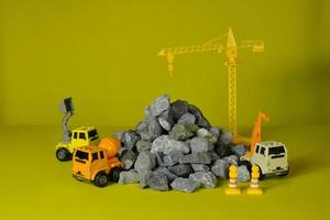 modeller simulator på gul bakgrund, byggfordon leksaker, lastbilar, grävmaskiner och kranar, platsarbete, transport av resursmaterial, sten, sten och murbruk, byggd fastighetsutvecklingsverksamhet foto