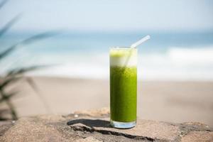 hälsosam grön juice på stranden foto