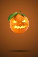 färsk apelsin som ett pumpor huvud flyger på pastell orange bakgrund. kreativa glad halloween semester koncept. halloween party gratulationskort. minimal säsong koncept. foto