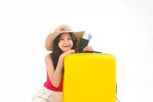 porträtt av ung vuxen sydostasiatisk kvinna med gult resbagage och pass på vit isolerad bakgrund foto