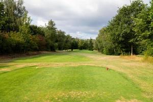 golfbana med gräs och moln på himlen foto