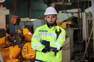 industriingenjörer i hårda hattar.jobbar på den tunga industrins tillverkningsfabrik. industriarbetare inomhus i fabrik. man som arbetar i en industri foto