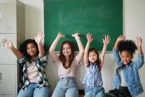 glada små flickor mot svarta tavlan med tillbaka till skolan foto