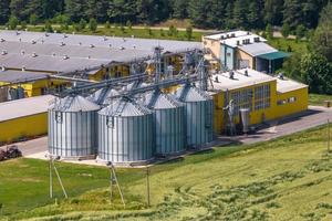 silos och agroindustriellt boskapskomplex på agrobearbetnings- och tillverkningsanläggning med modern spannmålshiss. hönsfarm. rader av hönshus foto