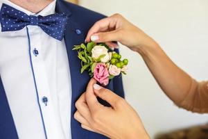 bruden sätter brudgummen på boutonniere från rosa och whote rose på bröllopsdagen foto