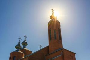 solens strålar genom kupolen av ortodoxa kristna kyrkan av rött tegel i solig sommardag foto