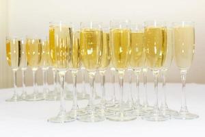 massor av suddiga glas med champagne på mottagningsfestbordet på ljus bakgrund foto