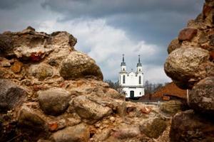 modernt tempel bakom ruinerna av ett gammalt medeltida slott från storhertigdömet Litauens tider i Vitryssland en molnig dag före stormen foto