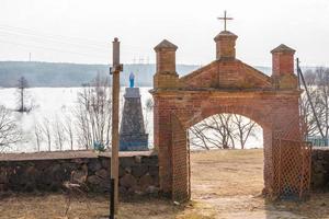 port med ett kors nära en gammal kyrka med utsikt över en vacker sjö foto