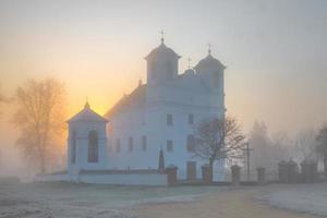 vacker katolsk kyrka i tidig höstdimma morgon foto