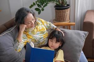 porträtt av en äldre kvinna och barnbarn som läser en bok för att förbättra läsförmågan och familjeaktiviteter. foto