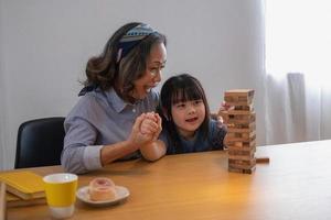 mormor och barnbarn spelar spel. blockwood pussel för att utveckla färdigheter för barnbarn och som en semesteraktivitet foto