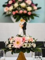 bröllopsbordsdekorationer. blommor, statyetter av bruden och brudgummen. foto