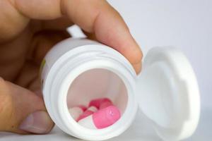 en burk med piller i en persons hand foto