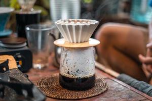 droppa kaffe, barista hälla vatten på kaffemalen med filter foto