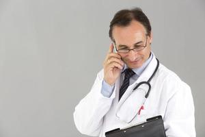 läkare vid mobiltelefonen tittar på hans urklipp