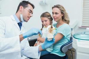 tandläkare med assistent som lär tjej hur man borstar tänder