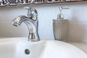 tvål och schampo dispensrar på vattenkran handfat med kran i dyra loft badrum foto