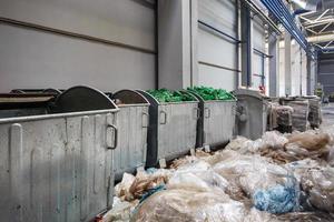 behållare med använda flaskor och plastbalar med skräp vid avfallsbehandlingsanläggning. återvinning separat och förvaring av sopor för vidare omhändertagande, sopsortering. foto