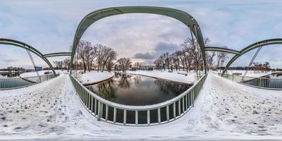 fullständig sömlös sfärisk vinterpanorama 360 graders vinkelvy nära järn stålramkonstruktion av gångbro över floden i Cite Park i ekvirektangulär projektion, vr ar innehåll foto