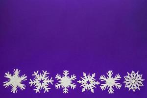 vitt pappers snöflingor olika former och storlekar på violett bakgrund. toppvy. foto